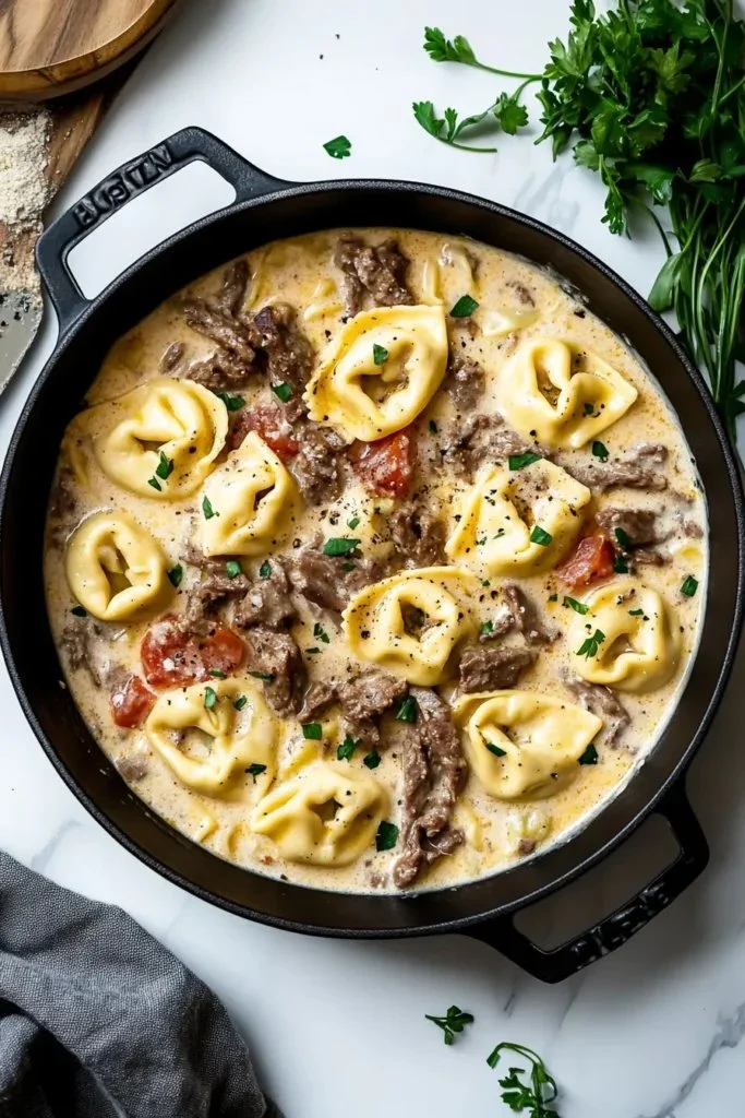 Cheesesteak tortellini in creamy provolone sauce served in a bowl.