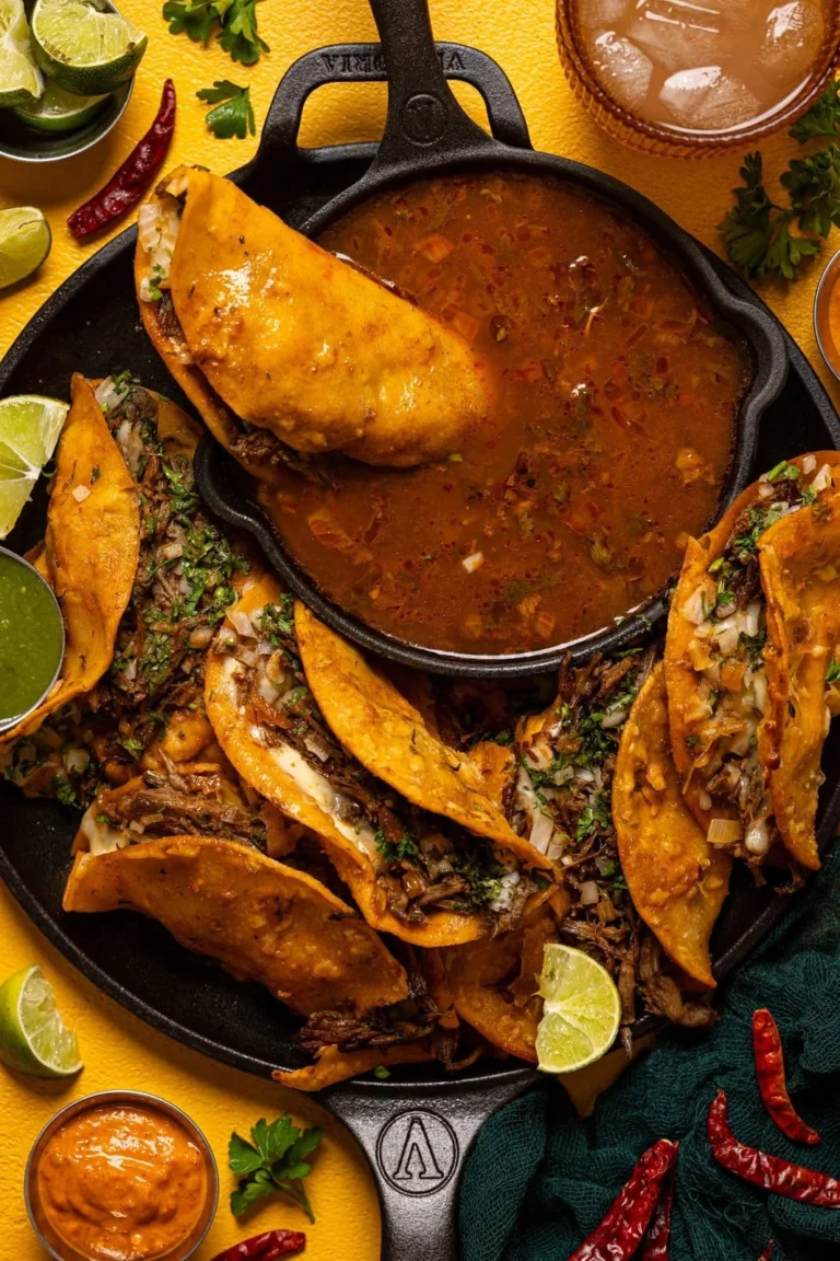 Delicious birria tacos served with dipping sauce and fresh toppings