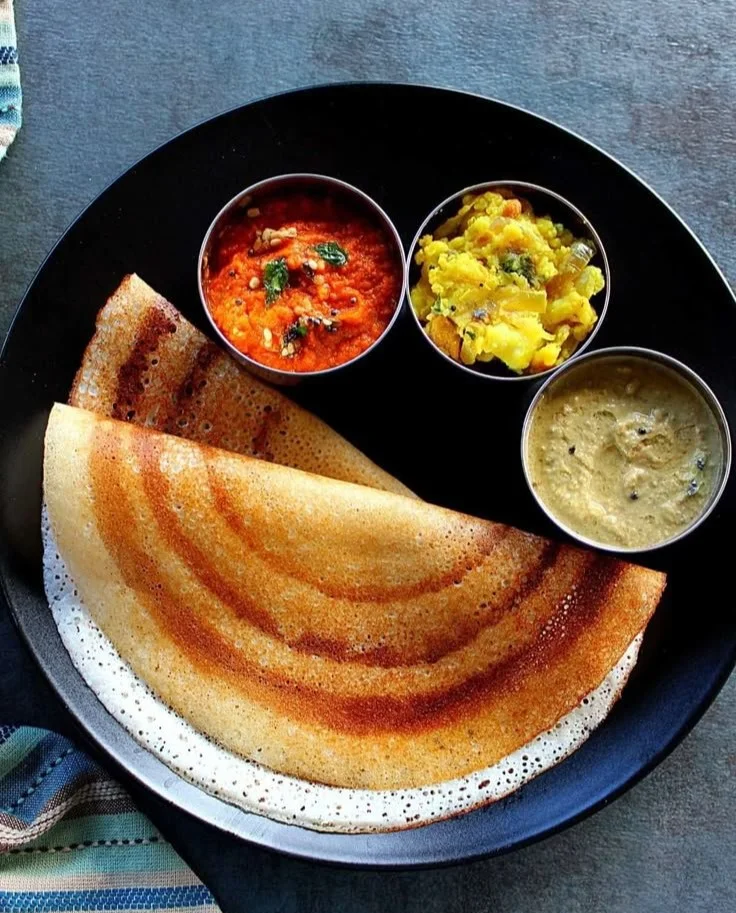 Golden brown crispy dosa served with chutney and sambar on a plate