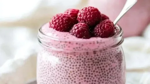 Bowl of Raspberry Chia Pudding topped with fresh raspberries and maple syrup