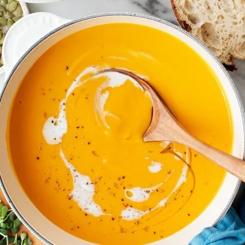 Bowl of creamy sweet potato soup topped with herbs and spices