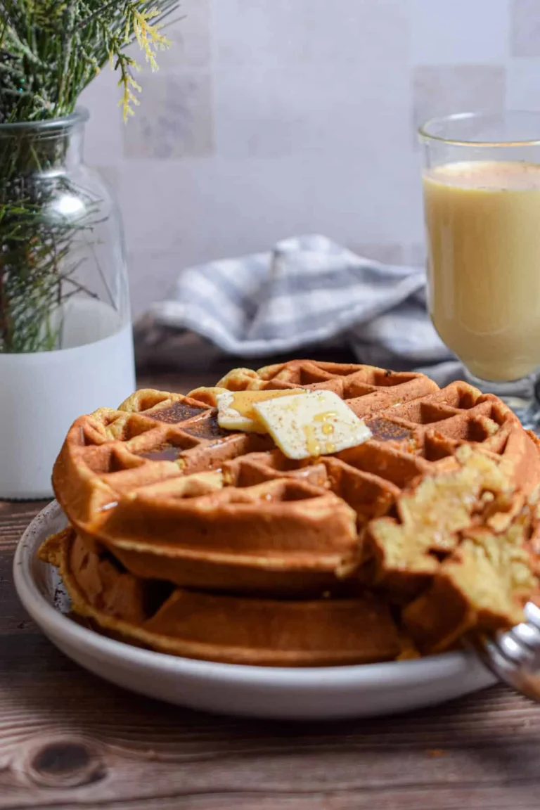 Festive eggnog waffles served with whipped cream and dusted with cinnamon