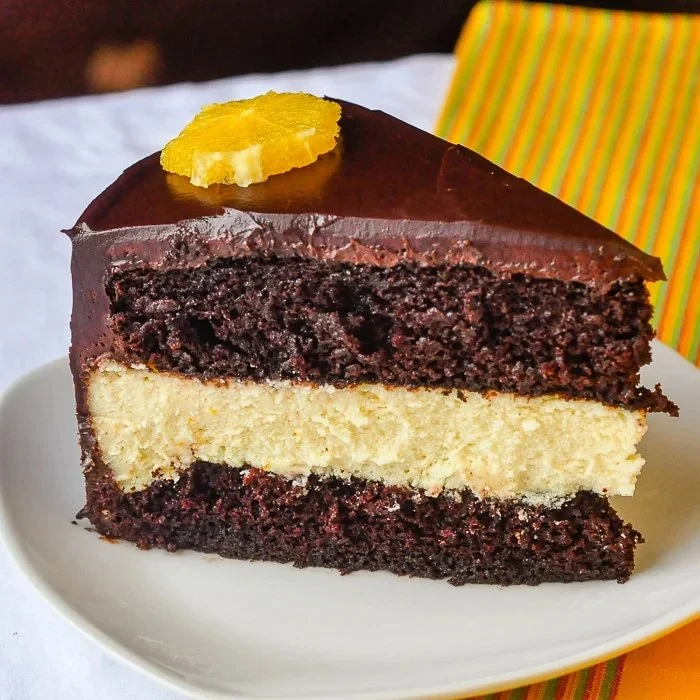 Decadent chocolate orange cheesecake layer cake garnished with orange slices and chocolate shavings.
