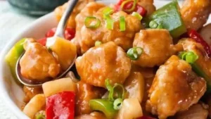 Baked sweet and sour chicken served with colorful vegetables on a plate