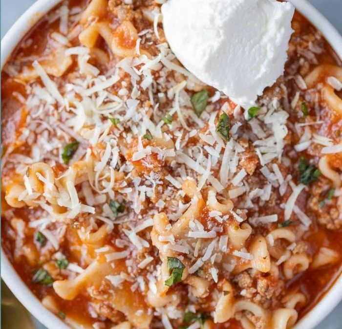 Delicious high protein lasagna soup in a bowl, garnished with cheese and herbs.
